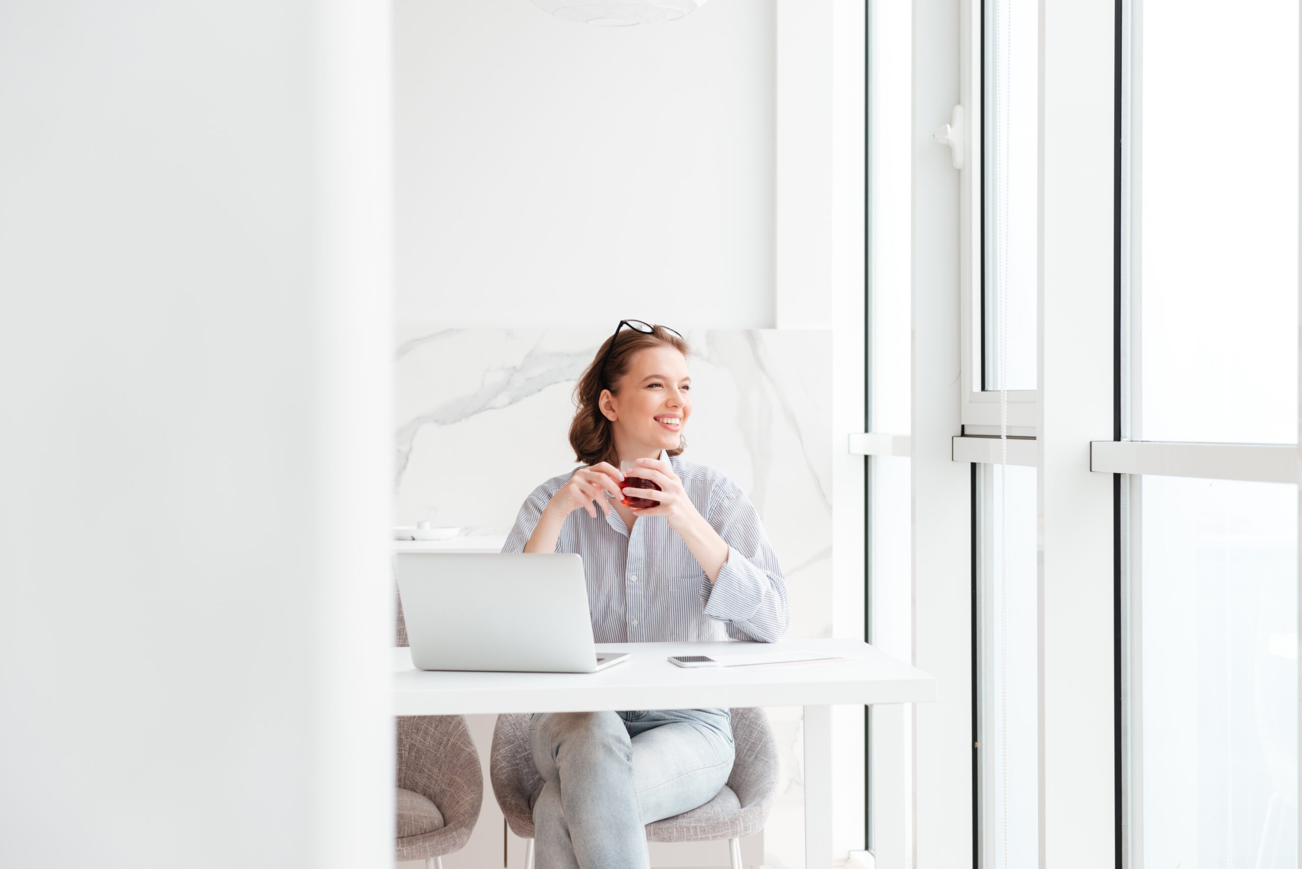 Young attractive brunette woman holding cup of tea while sitting